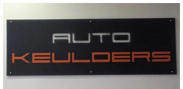 Het naambord van Auto Keulders aan de muur in de werkplaats
